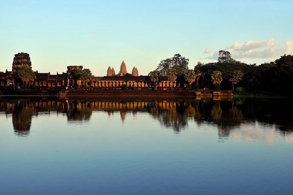 Angkor Wat's west front in late-afternoon light, reflected in the moat.