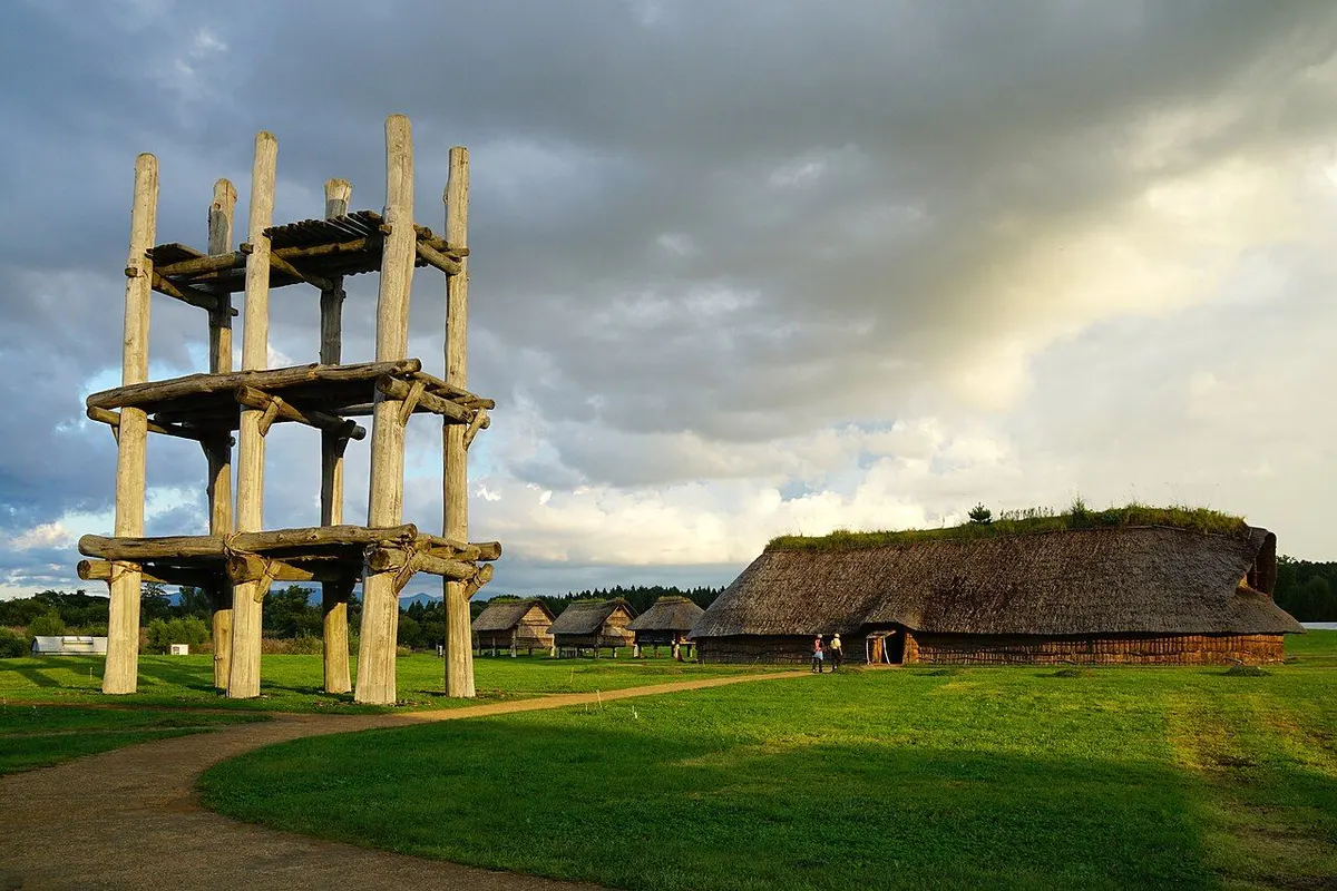 The reconstructed six-pillar wooden tower and a large thatched longhouse on the lawns of the Sannai Maruyama Site.
