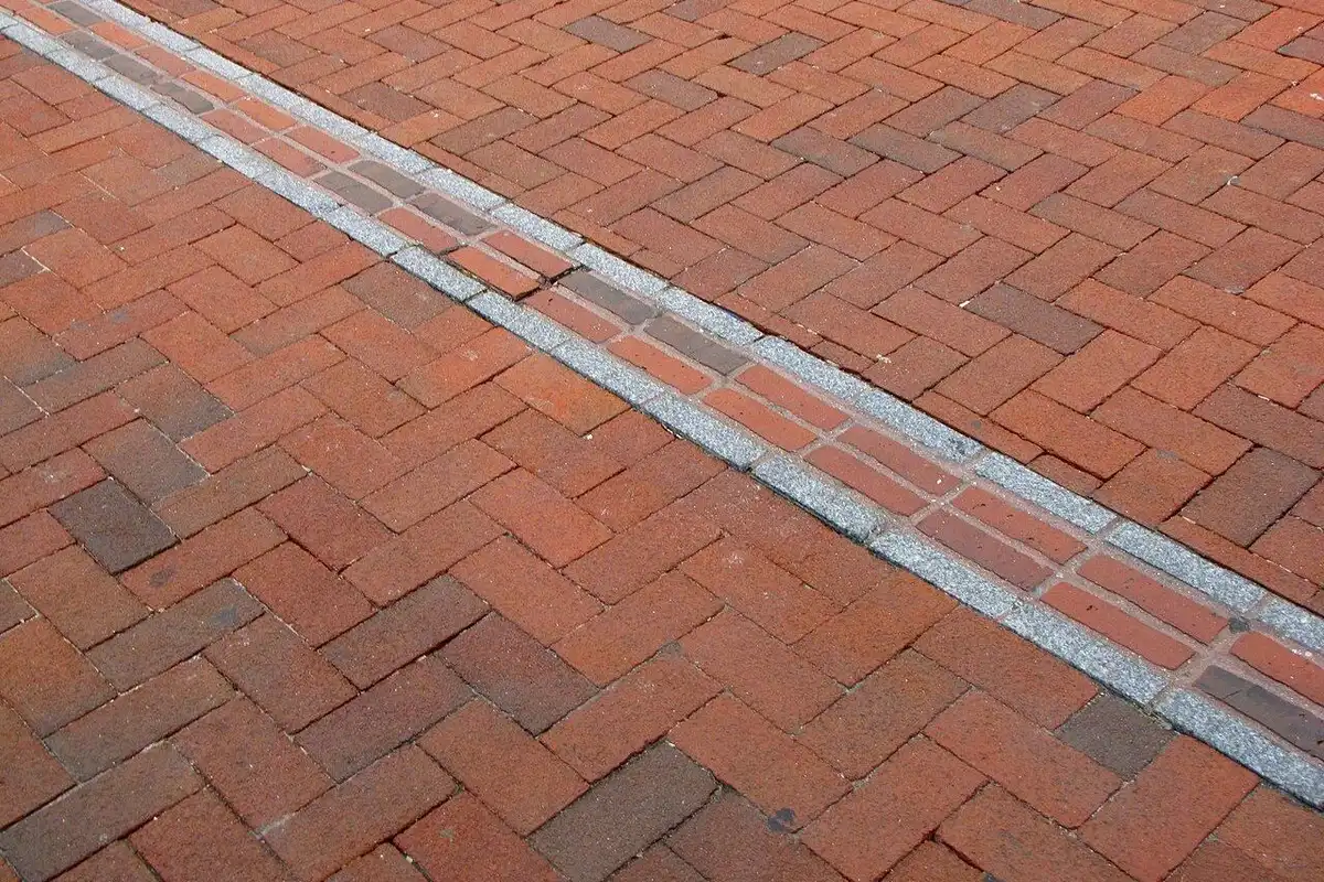 The red-brick line of the Freedom Trail running across a brick sidewalk.