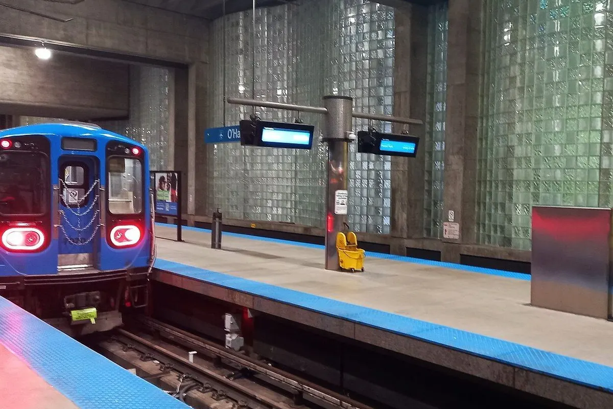 A blue Blue Line train waiting at the underground platform with glass-block walls.