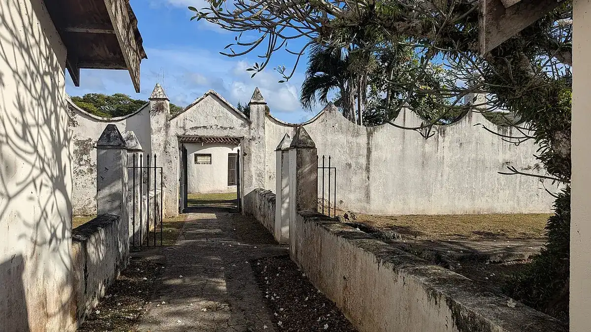Old whitewashed stone walls and gateway at Plaza de España in Hagåtña