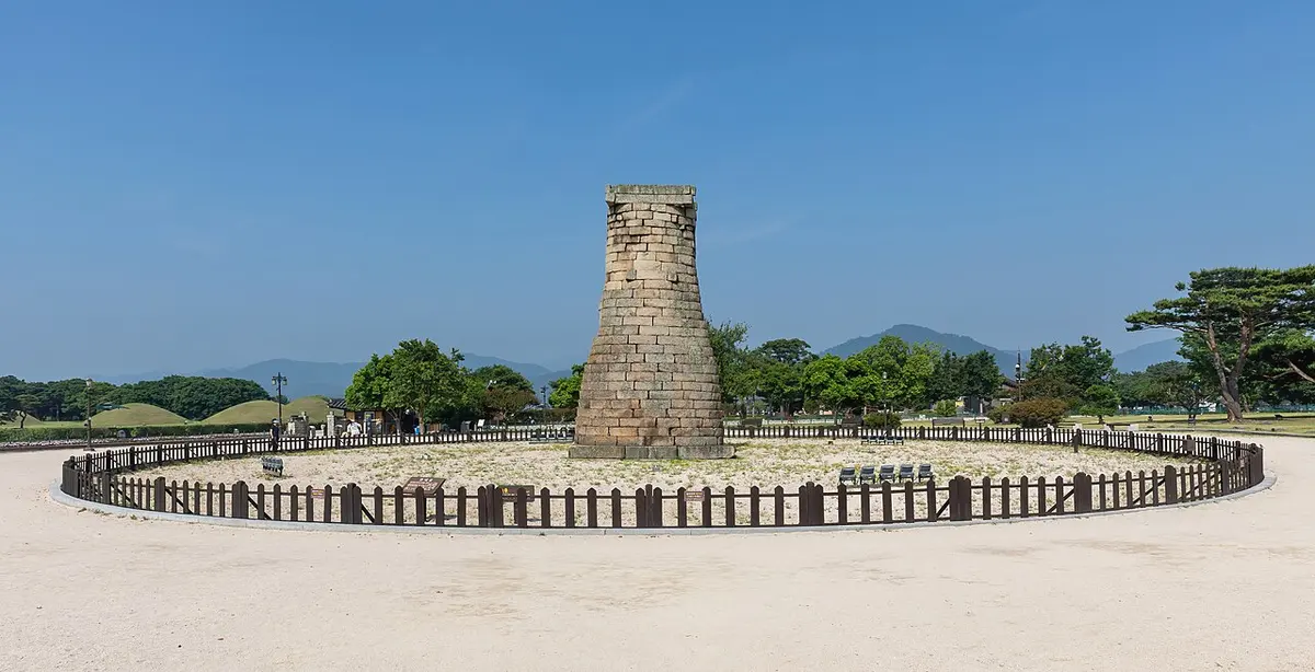 The stone Cheomseongdae Observatory inside its circular fence under a clear blue sky in Gyeongju.
