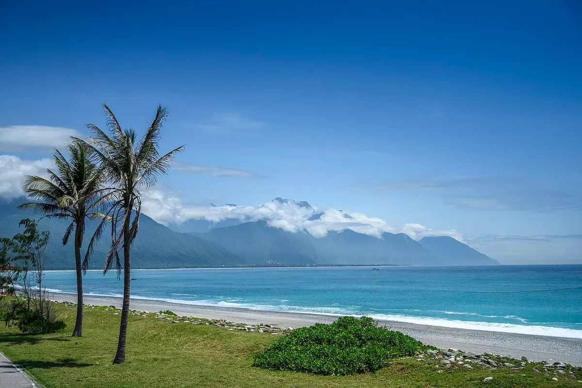 The curving Qixingtan Beach with cloud-capped mountains behind