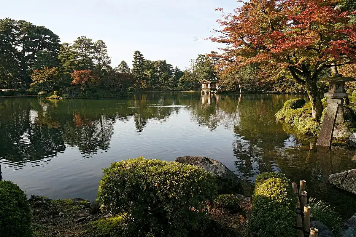 Red maples and a stone lantern by the pond in Kenrokuen in autumn.