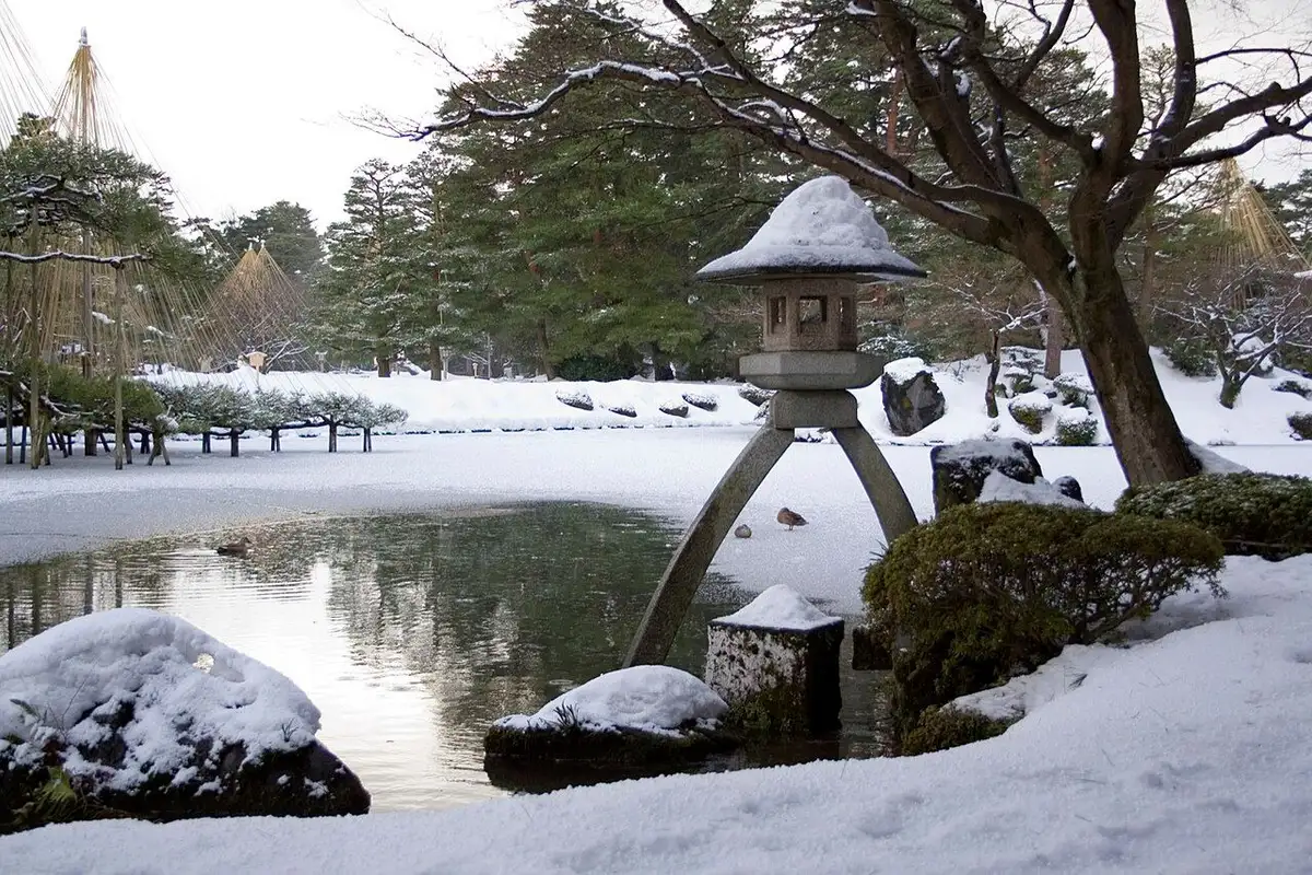 Snow on the Kotoji stone lantern and the trees by the pond at Kenrokuen in winter.