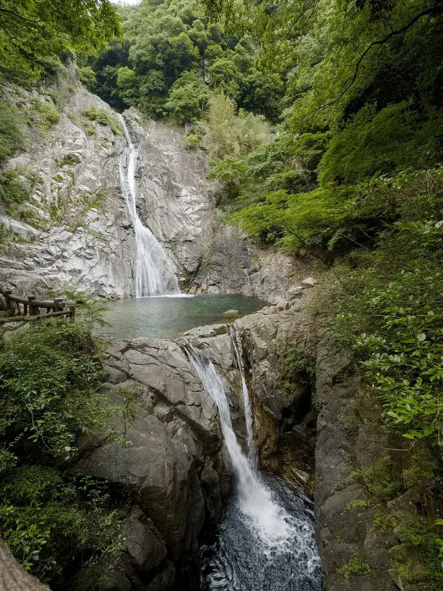 Nunobiki Falls dropping in two tiers down a rock face in green forest