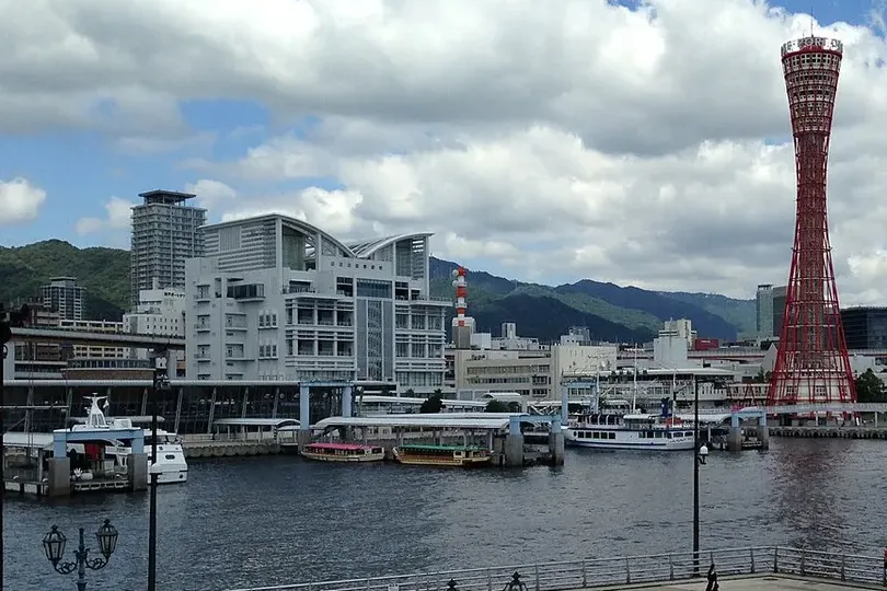 The red Kobe Port Tower and the Rokko Mountains seen across the harbor from Harborland