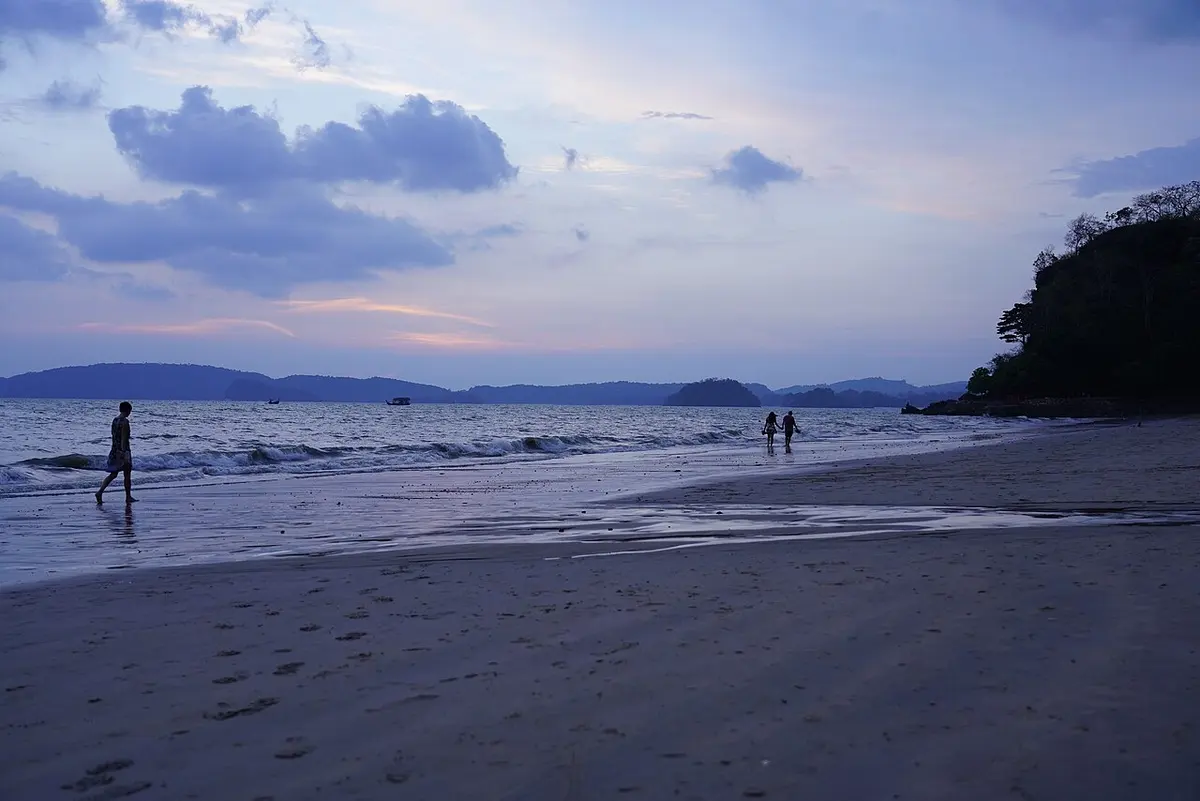 Ao Nang Beach in Krabi at dusk, with a wooded headland on the right