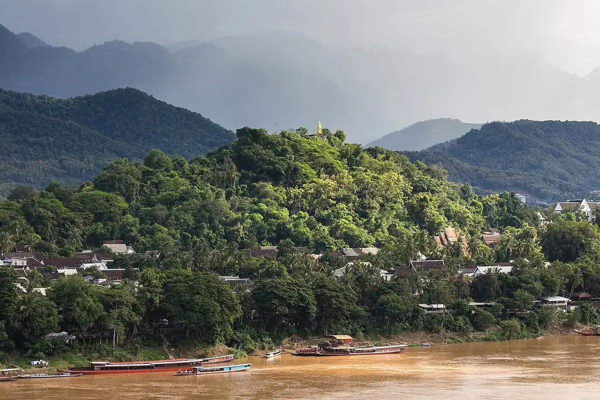 Luang Prabang's Mount Phou Si and boats on the Mekong seen from across the river