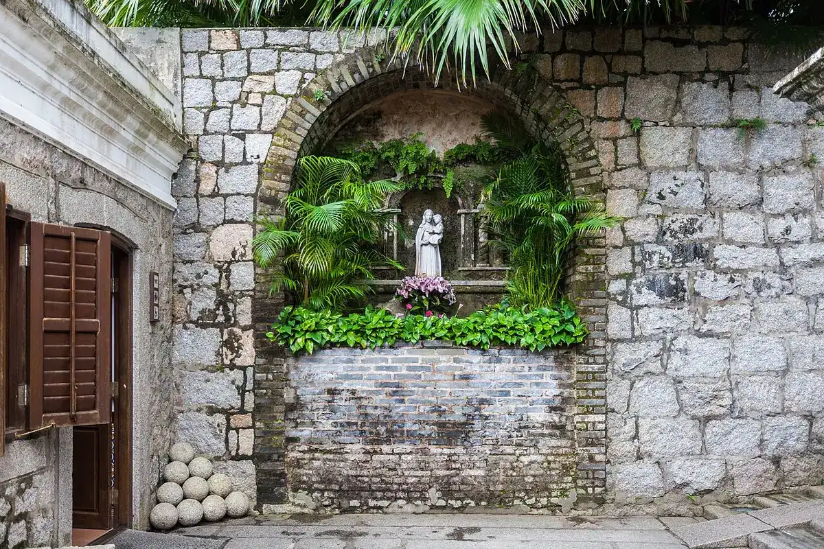 A stone wall with a niche at Mount Fortress in Macao, with round cannonballs piled below