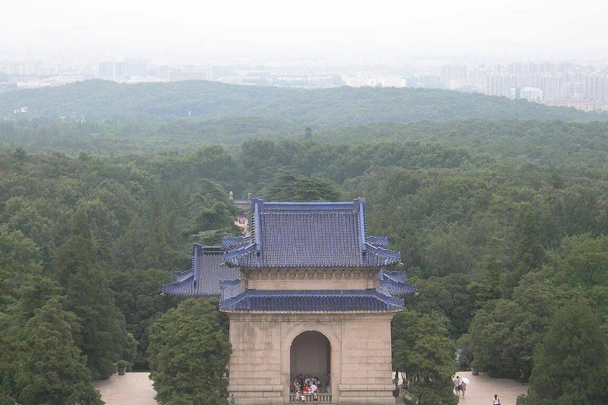 The blue-tiled stele pavilion of the Sun Yat-sen Mausoleum seen from above, surrounded by forest.