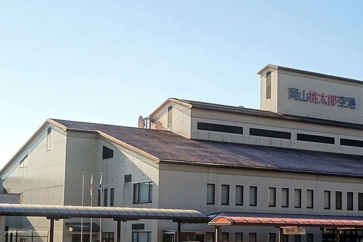 The Okayama Airport terminal building under a clear sky, with the bus stop canopies in front.