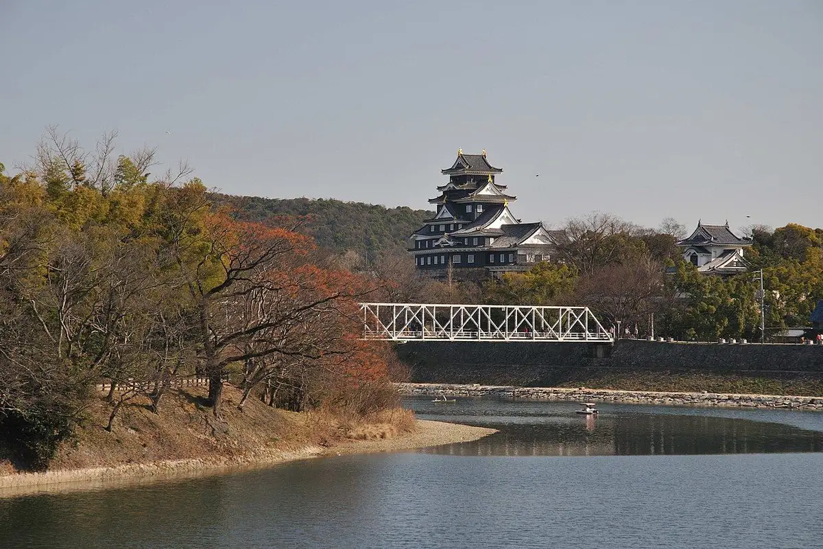 The black-walled keep of Okayama Castle standing above the far bank of the Asahi River.