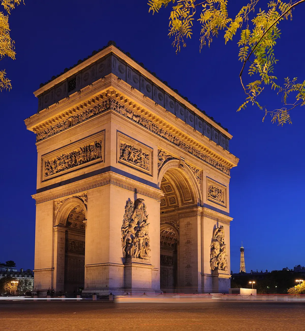 The Arc de Triomphe floodlit against a deep-blue twilight sky