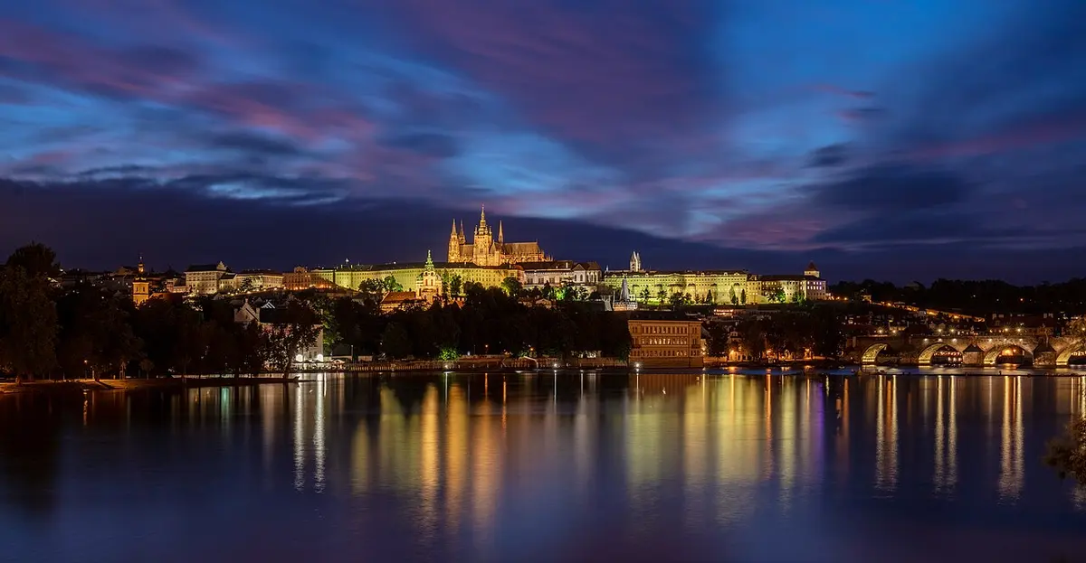 Prague Castle lit up at dusk and reflected in the Vltava