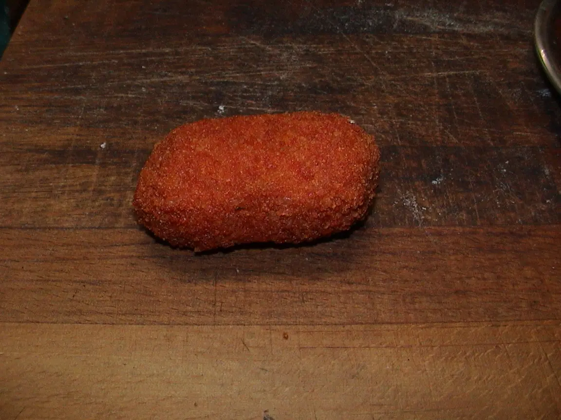 A golden fried supplì on a wooden board