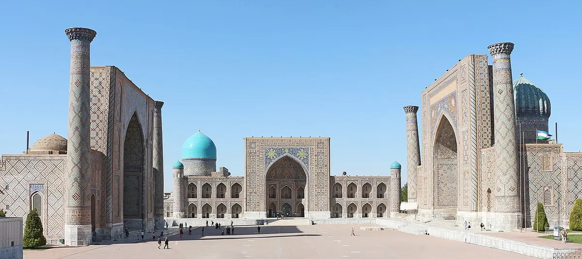 Registan Square in Samarkand, framed by three madrasahs with tiled portals and blue domes.
