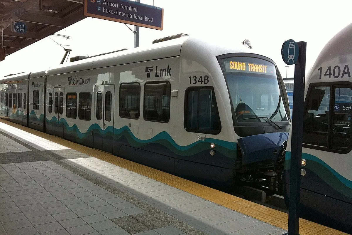A Link light rail train at the platform beneath an "Airport Terminal" direction sign.
