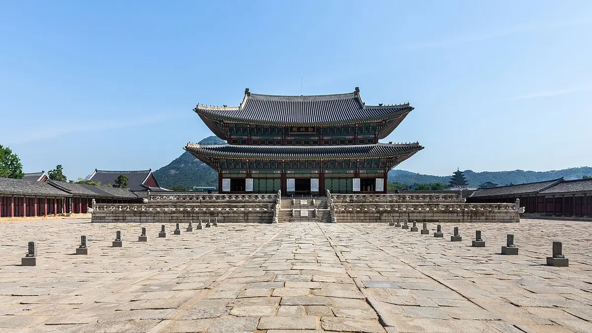 Front view of Geunjeongjeon throne hall at Gyeongbokgung Palace and its stone-paved courtyard under a blue sky