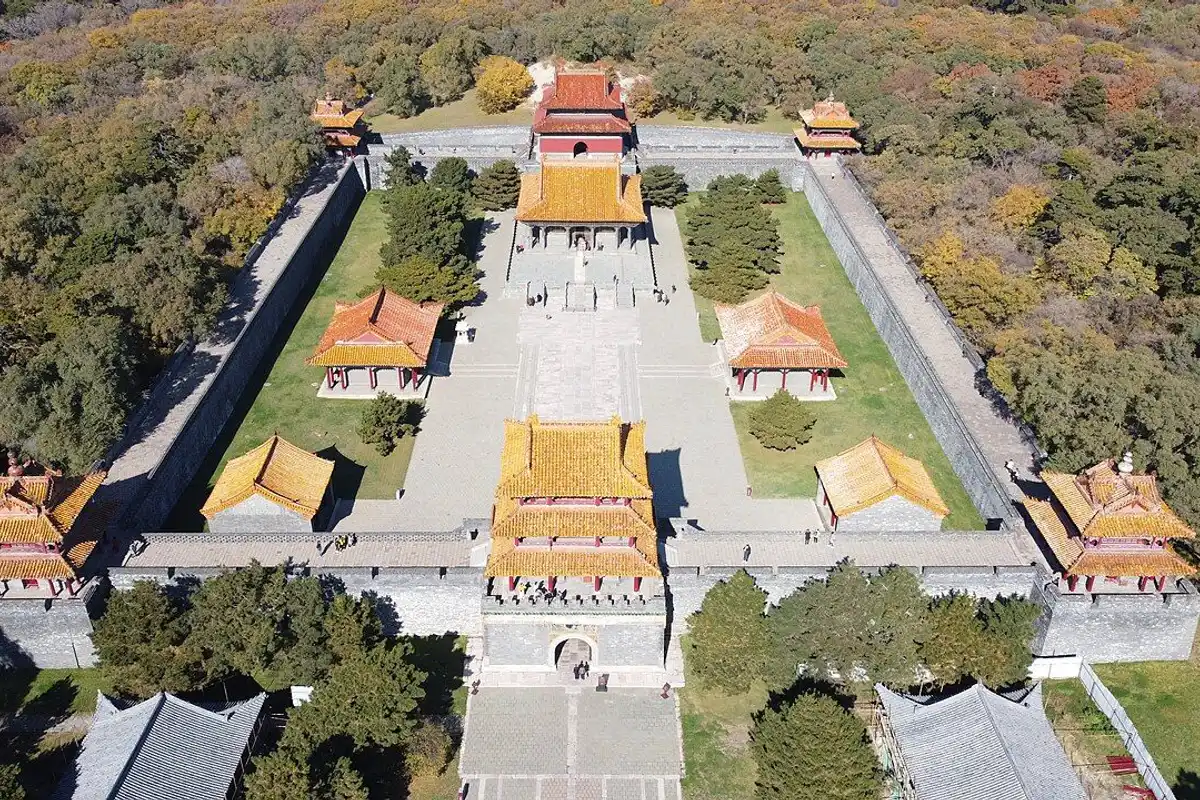 Aerial view of the yellow-roofed halls and walls of the Zhaoling Tomb surrounded by forest.