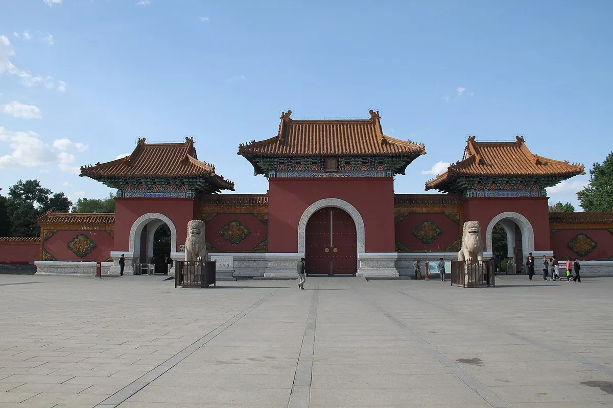 The red three-arched main gate of the Zhaoling Tomb with stone lions and a wide plaza.