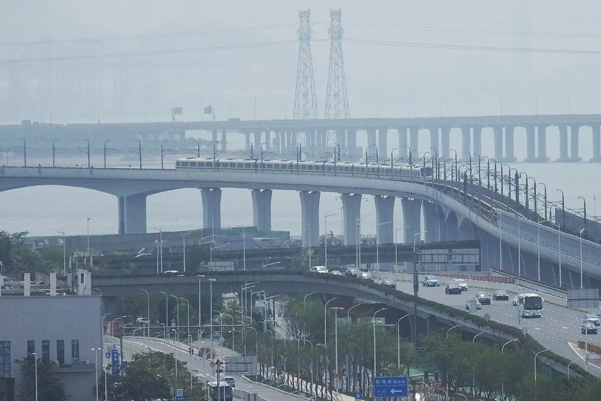 A Line 11 train running on an elevated track by the sea, with roads below.