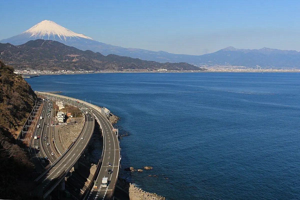 Roads curving along the coast below Satta Pass, with Suruga Bay and snow-capped Mt Fuji beyond.