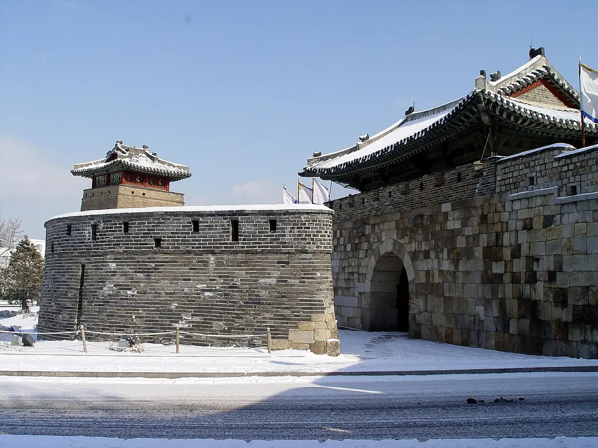 Hwaseomun Gate and the Seobuk Gongsimdon watchtower of Hwaseong Fortress with snow on the ground.