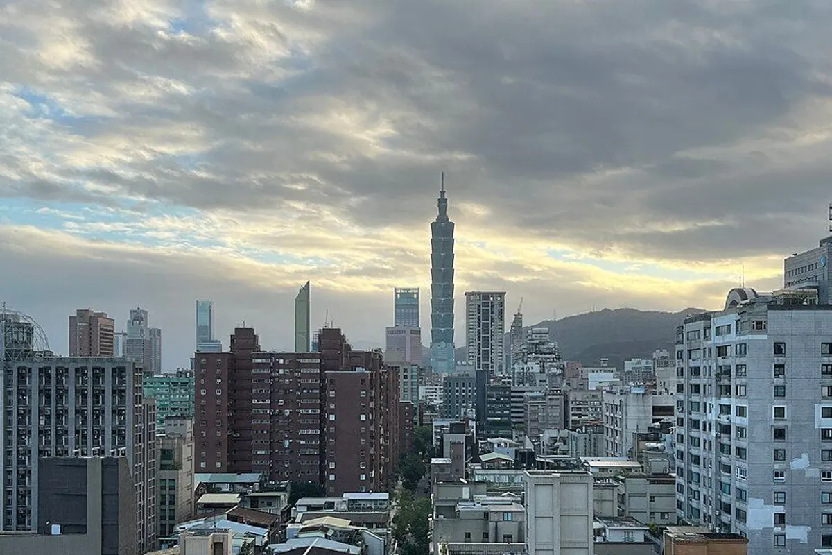 Taipei 101 towering over the city's buildings under morning clouds.