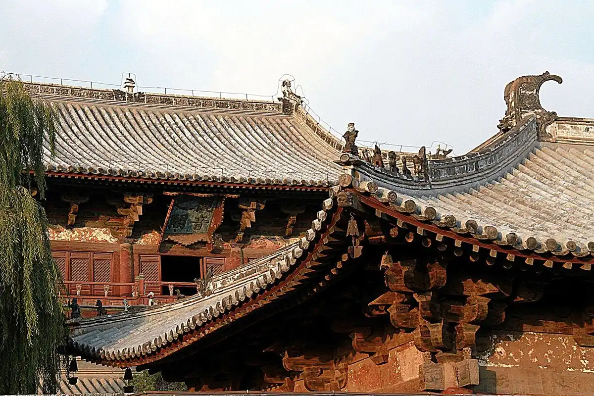 The sunlit roof of the Dule Temple gate, with the eaves of the Guanyin Pavilion rising behind it.