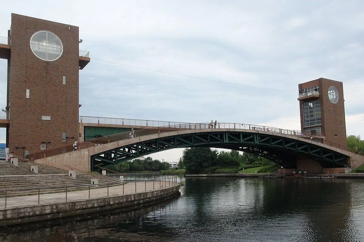 The arched Tenmon Bridge over the canal between two brick towers with round windows.