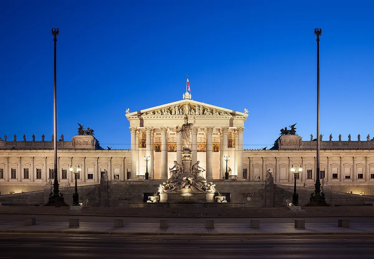 The Austrian Parliament Building lit up under a blue evening sky