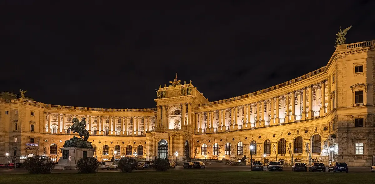 The curved facade of the Neue Burg wing of the Hofburg lit at night