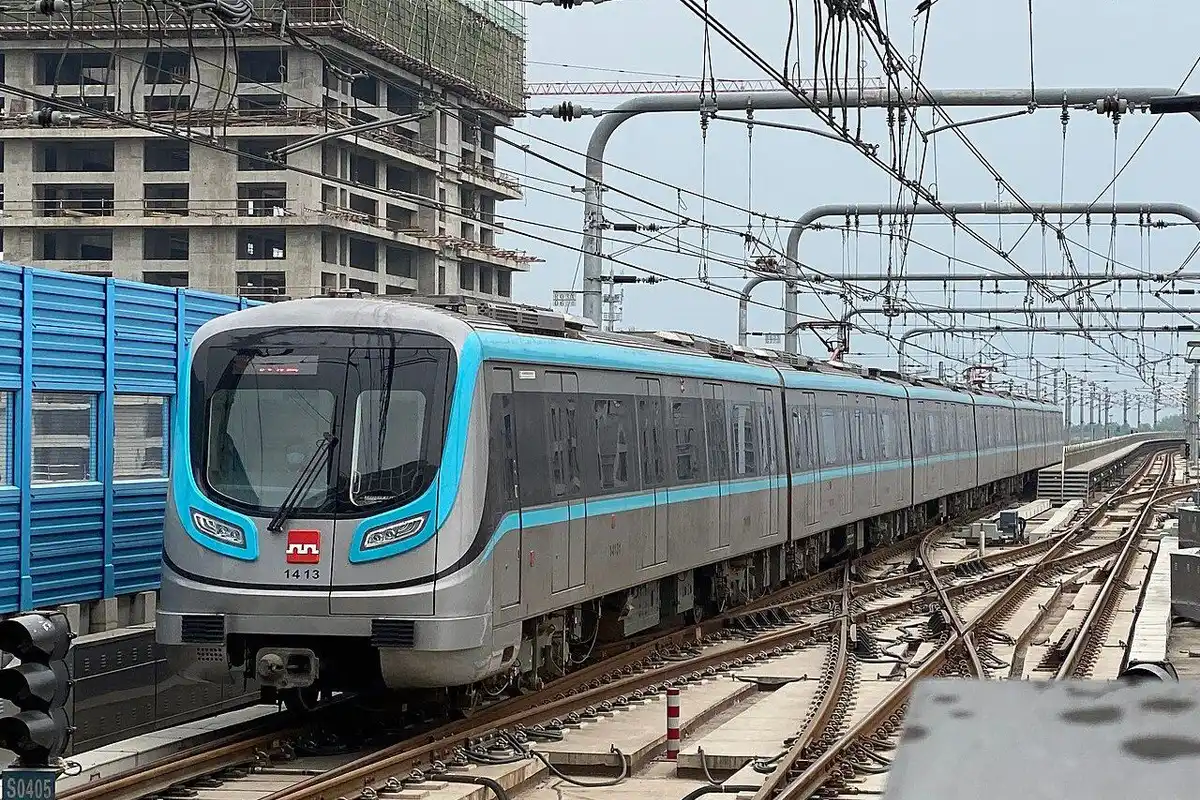 A silver and turquoise Line 14 train pulling into a station on an elevated track.
