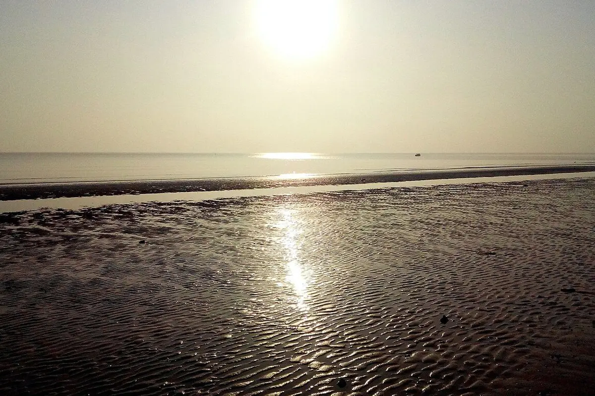 The morning sun lighting rippled sand and a calm sea on a Yantai beach.
