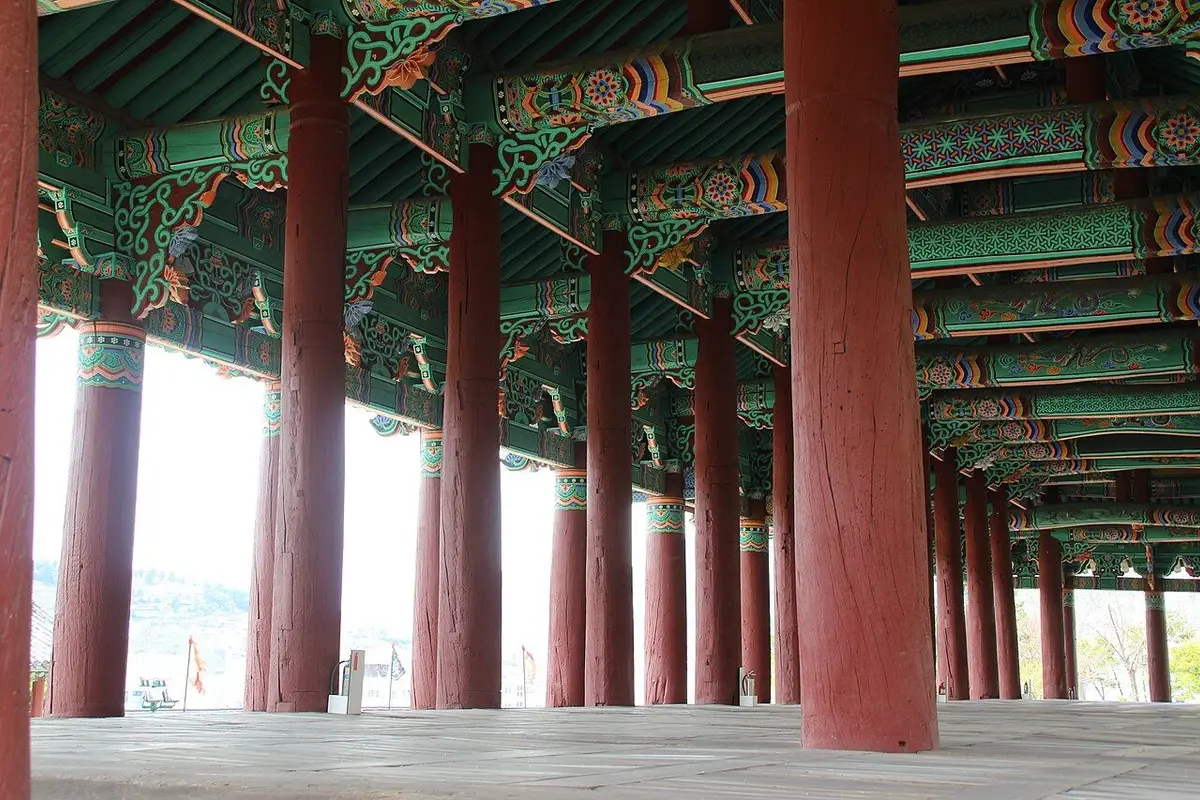 Rows of red wooden columns inside Jinnamgwan in Yeosu, under beams and rafters painted in green and orange dancheong patterns.