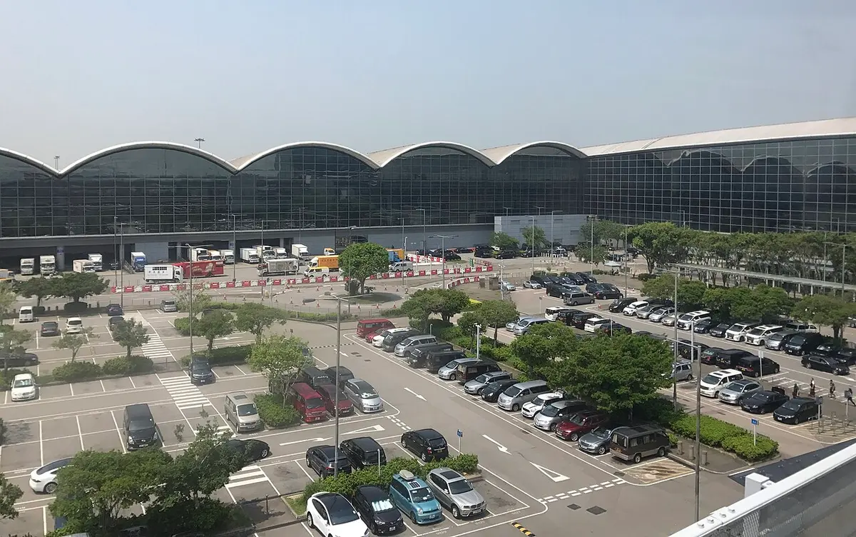 Exterior of Hong Kong International Airport Terminal 1 and its wave-shaped roof, seen across the car park