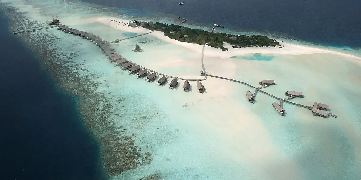Aerial view of a small island ringed by coral reef in the Maldives