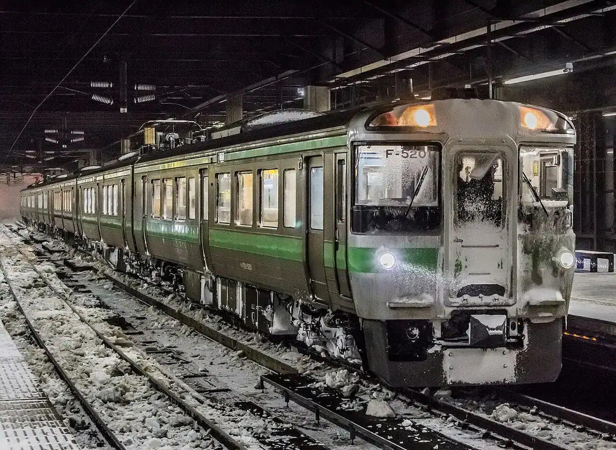 A snow-covered JR Hokkaido 721 series train at Sapporo Station at night.