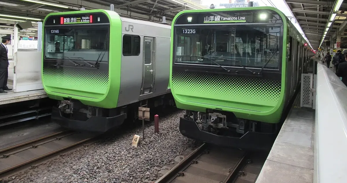 Two Yamanote Line E235 series trains side by side at Ikebukuro Station.